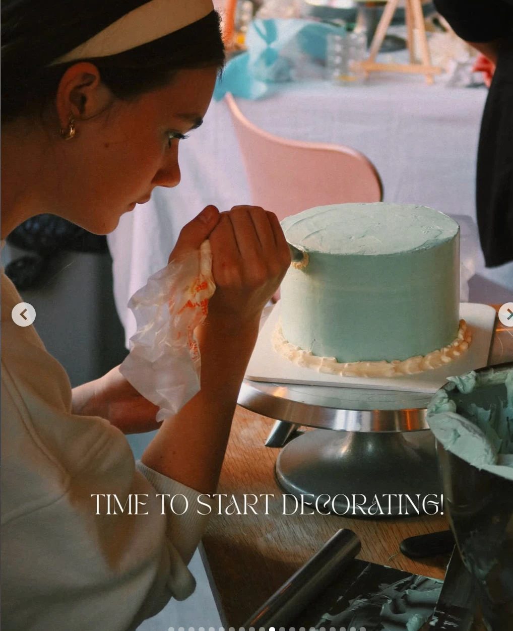 A Café Chiffon baker piping buttercream onto a pastel layer cake