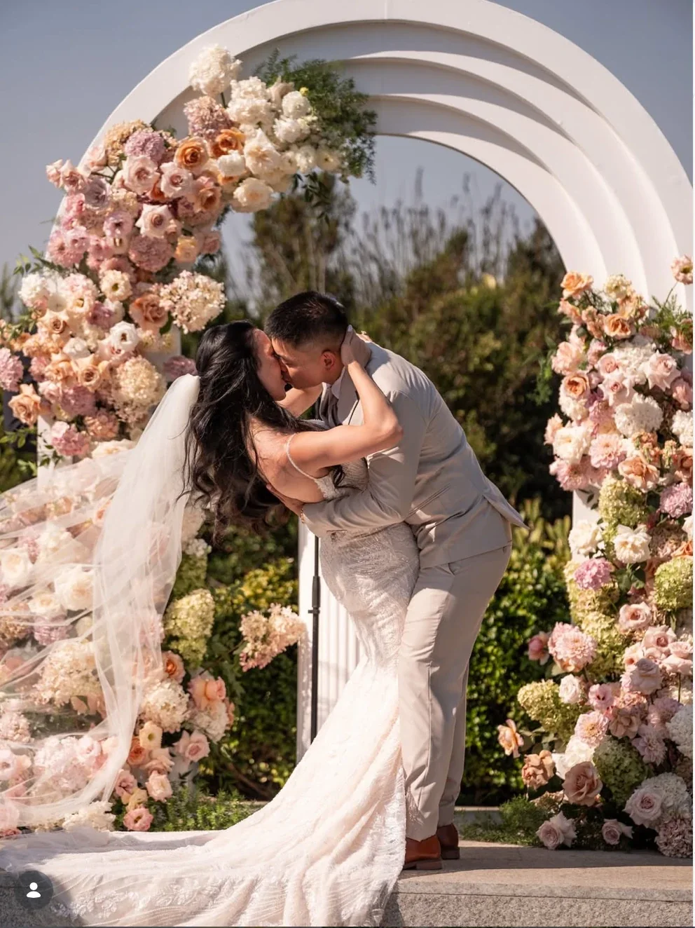 Blush and peach floral ceremony arch with couple